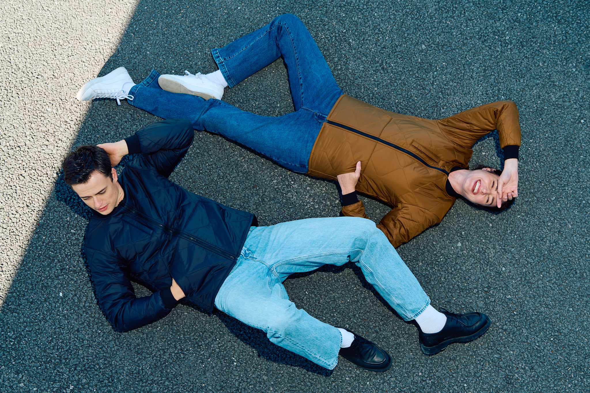 CX2 quilted jackets in navy and tan, two models shot from overhead on asphalt - on-location editorial by Fisheye Studio Toronto